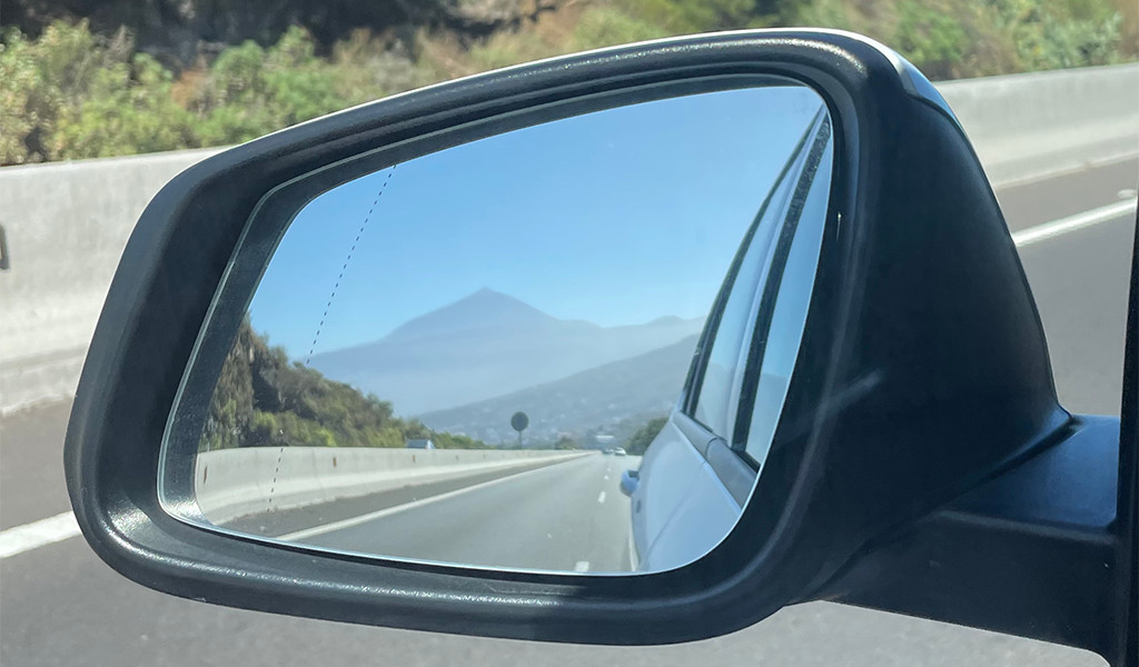Reflectie van de berg Teide in de achteruitkijkspiegel van een auto op de weg op Tenerife.