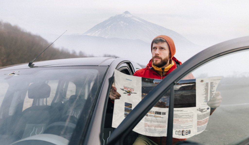 De man raadpleegt een kaart naast een auto met de berg Teide op de achtergrond, Tenerife.