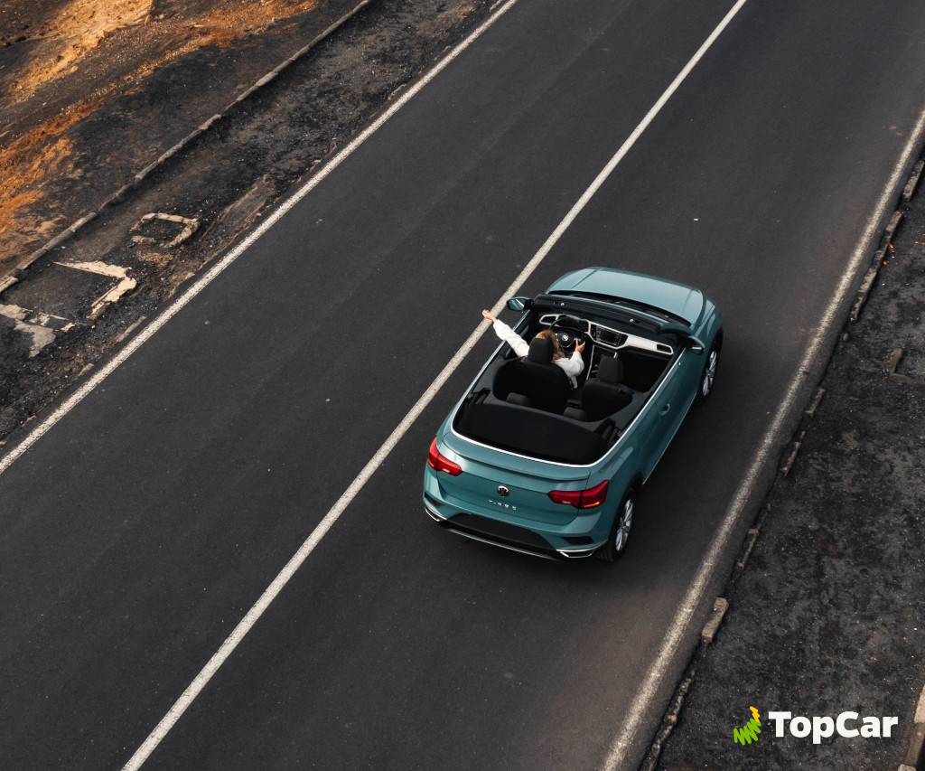 Persoon die in een blauwe cabriolet op de weg rijdt op Tenerife. Zichtbare tekst: TopCar.