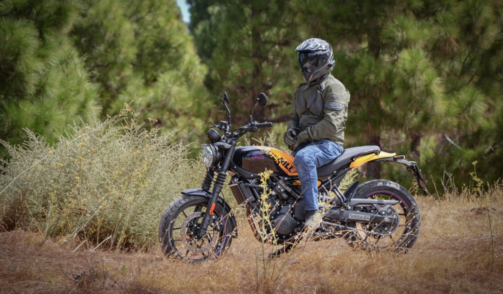 Persoon met een helm zittend op een motorfiets op een bosweg op Tenerife.