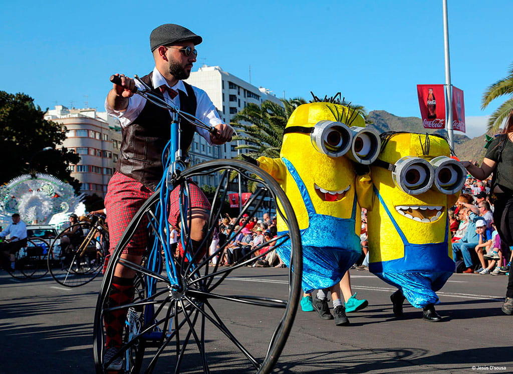 Parade met mensen verkleed als gele figuren en fietsers op een oude fiets op Tenerife.