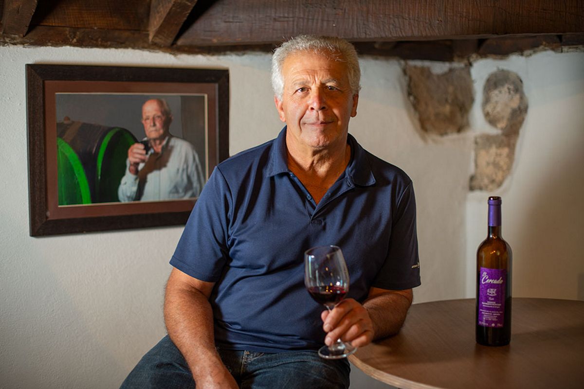 Man houdt een glas wijn vast naast fles en portret in de cantina van Tenerife.