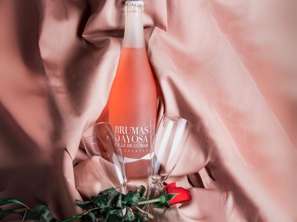 Fles Brumas De Ayosa Valle de Güímar mousserende wijn met glazen en rode roos.