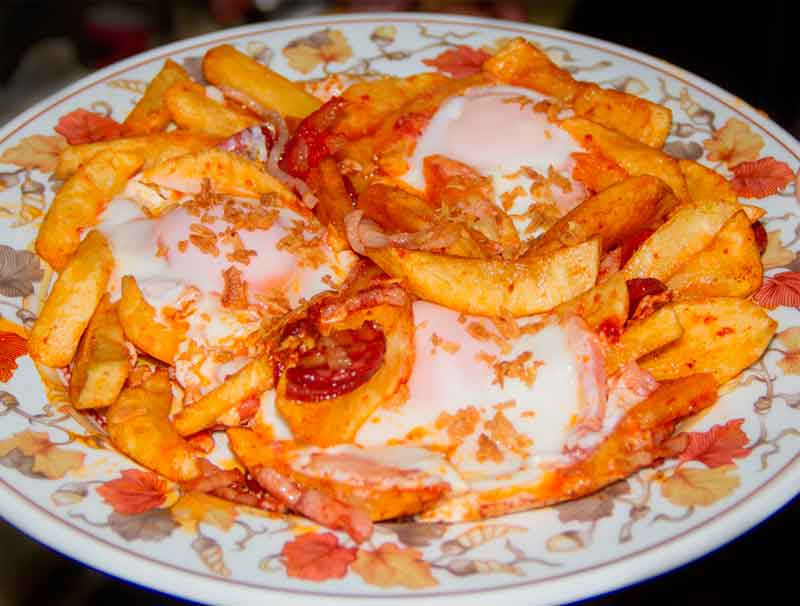 Frietjes met eieren en chorizo op een versierd bord op Tenerife.