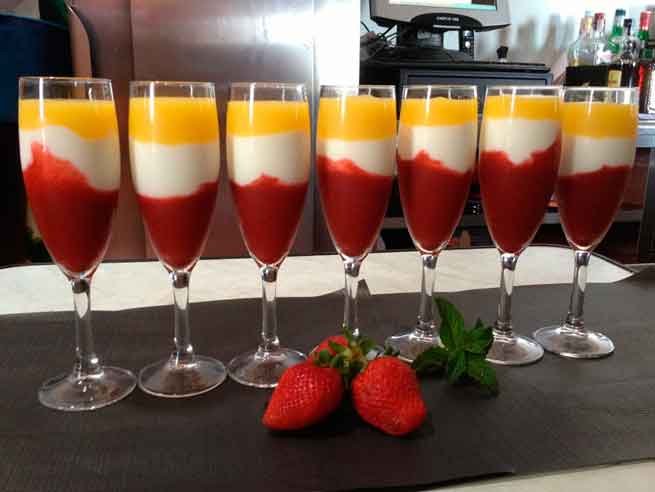 Dessertglazen met lagen aardbei en mango naast aardbeien op Tenerife.
