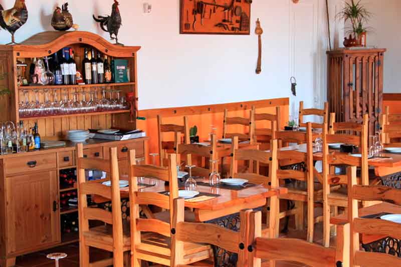 Restaurant op Tenerife met houten tafels en stoelen, en een plank met glazen.