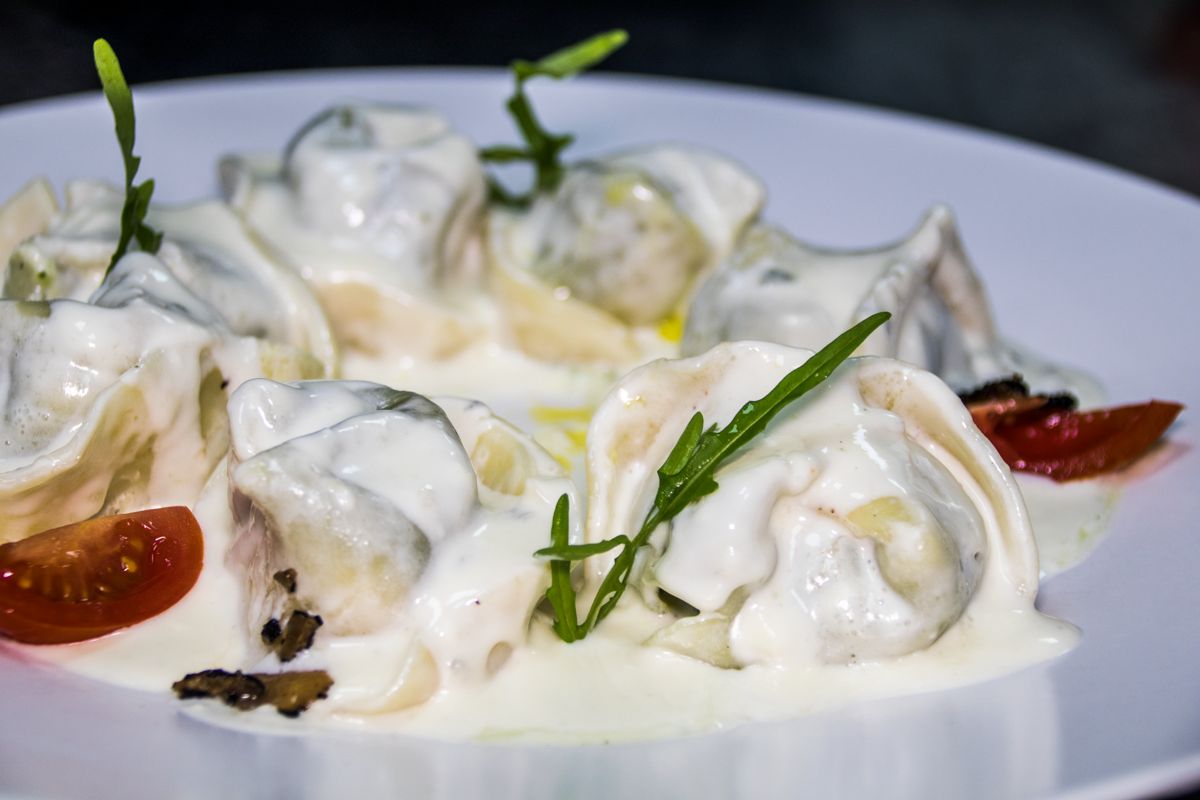 Pasta gevuld met witte saus en tomaat op een bord in Tenerife.