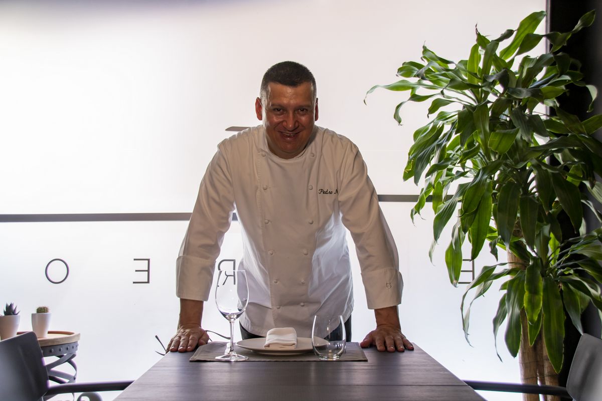 Chef in de keuken met plant en tafel gedekt in restaurant op Tenerife.