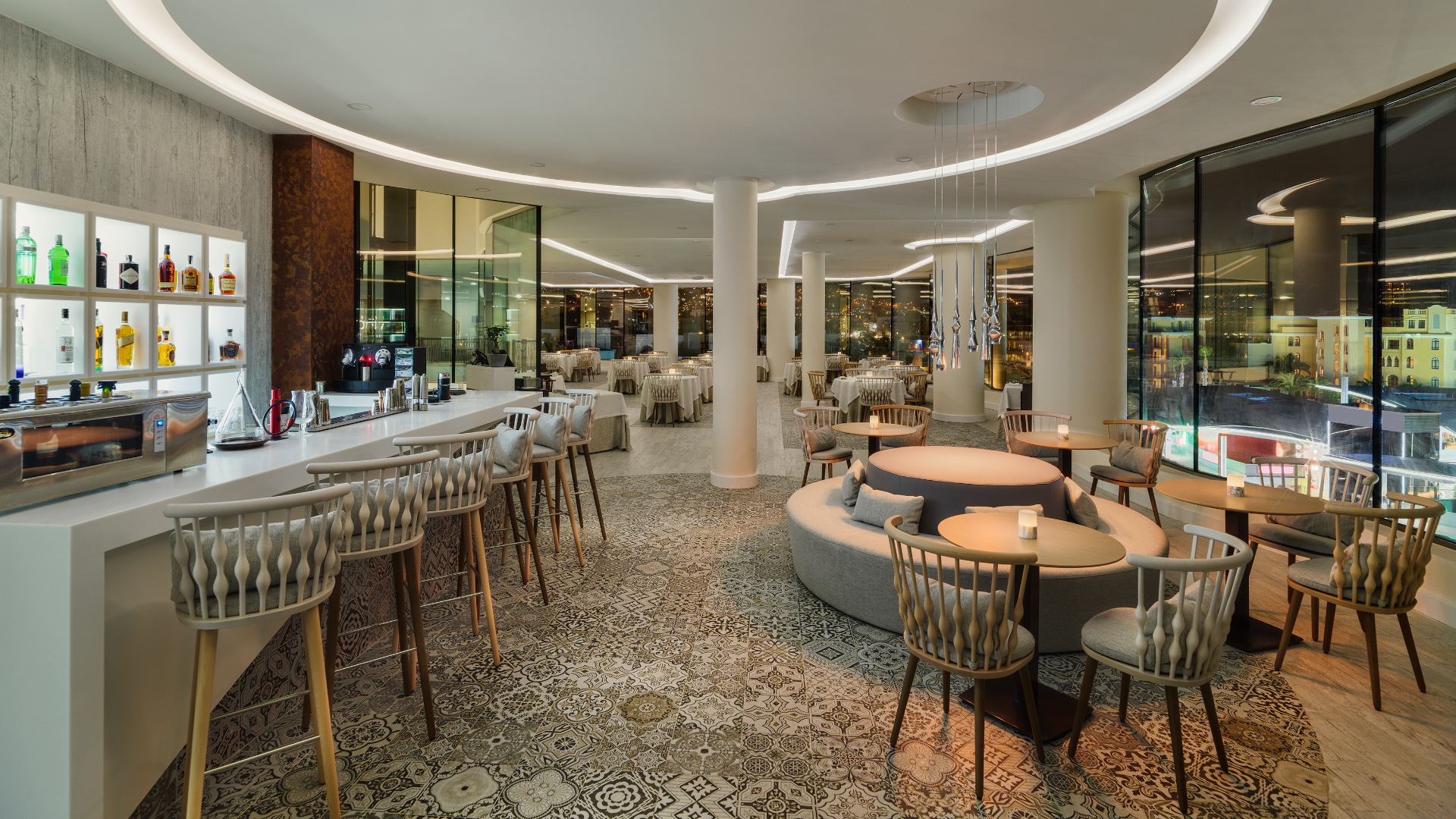Het interieur van een elegant restaurant op Tenerife, met een verlichte bar en tafels met stoelen.