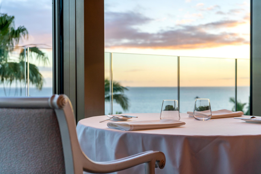 Tafel met glazen en servetten, zeezicht bij zonsondergang op een plek op Tenerife.