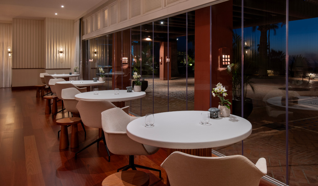 Eettafels en stoelen naast grote ramen in een elegant restaurant op Tenerife.