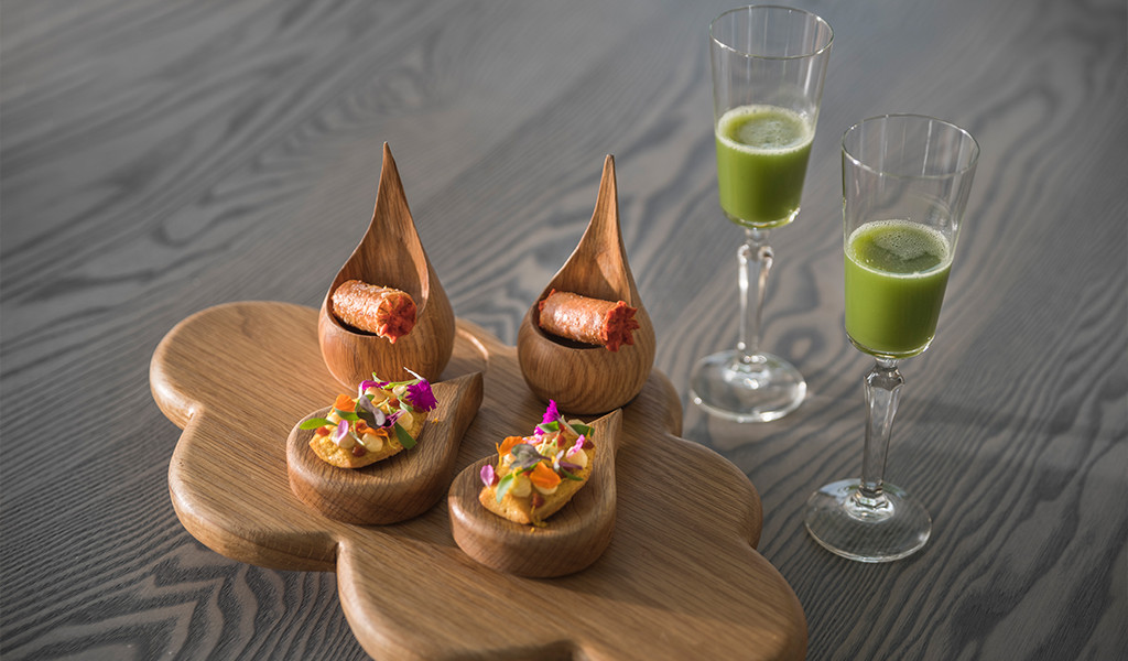 Verschillende gastronomische voorgerechten en glazen met groene sap op een bord op Tenerife.