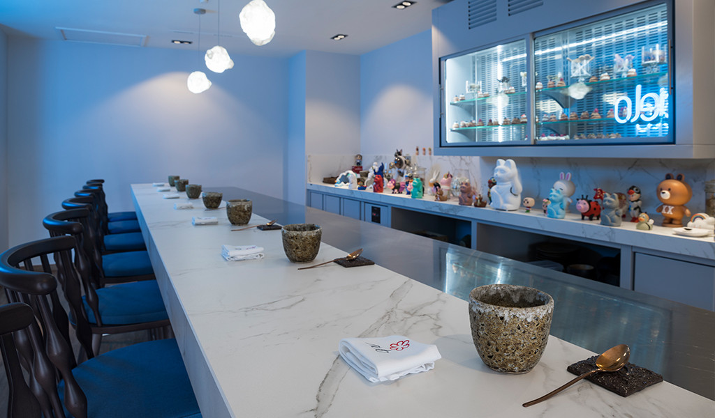 Sushibar met figuurdecoratie en blauwe stoelen in een restaurant op Tenerife.