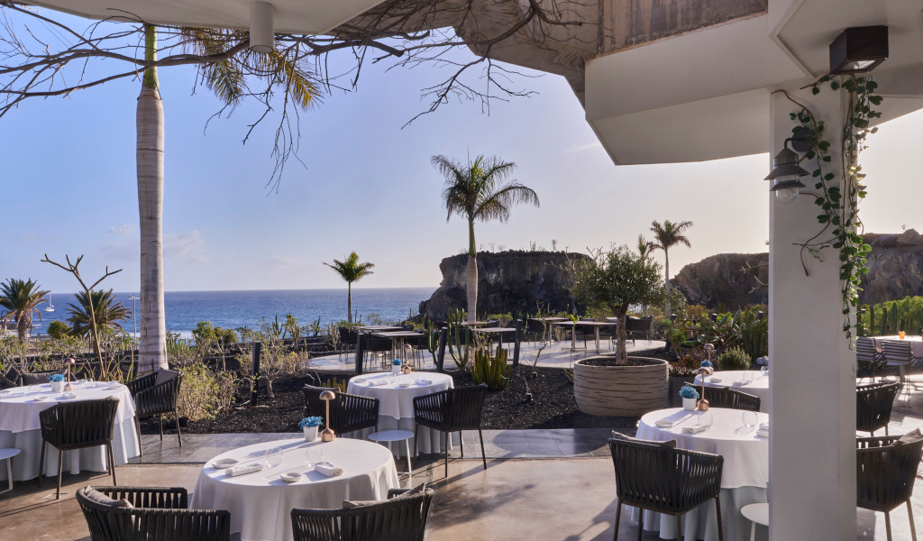 Restaurantterras met uitzicht op zee en palmbomen op Tenerife.