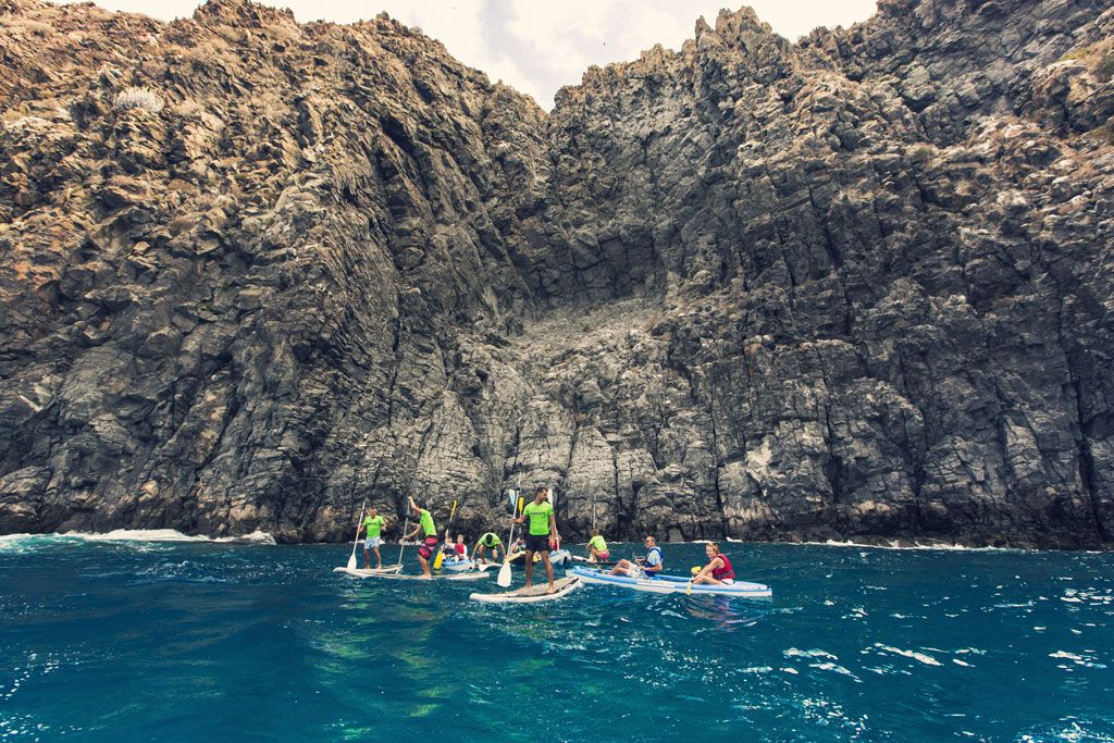 Mensen peddelen surfen voor kliffen op Tenerife.