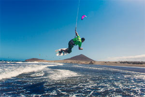 Persoon die kitesurft in Playa El Médano, Tenerife, met een heuvel op de achtergrond.