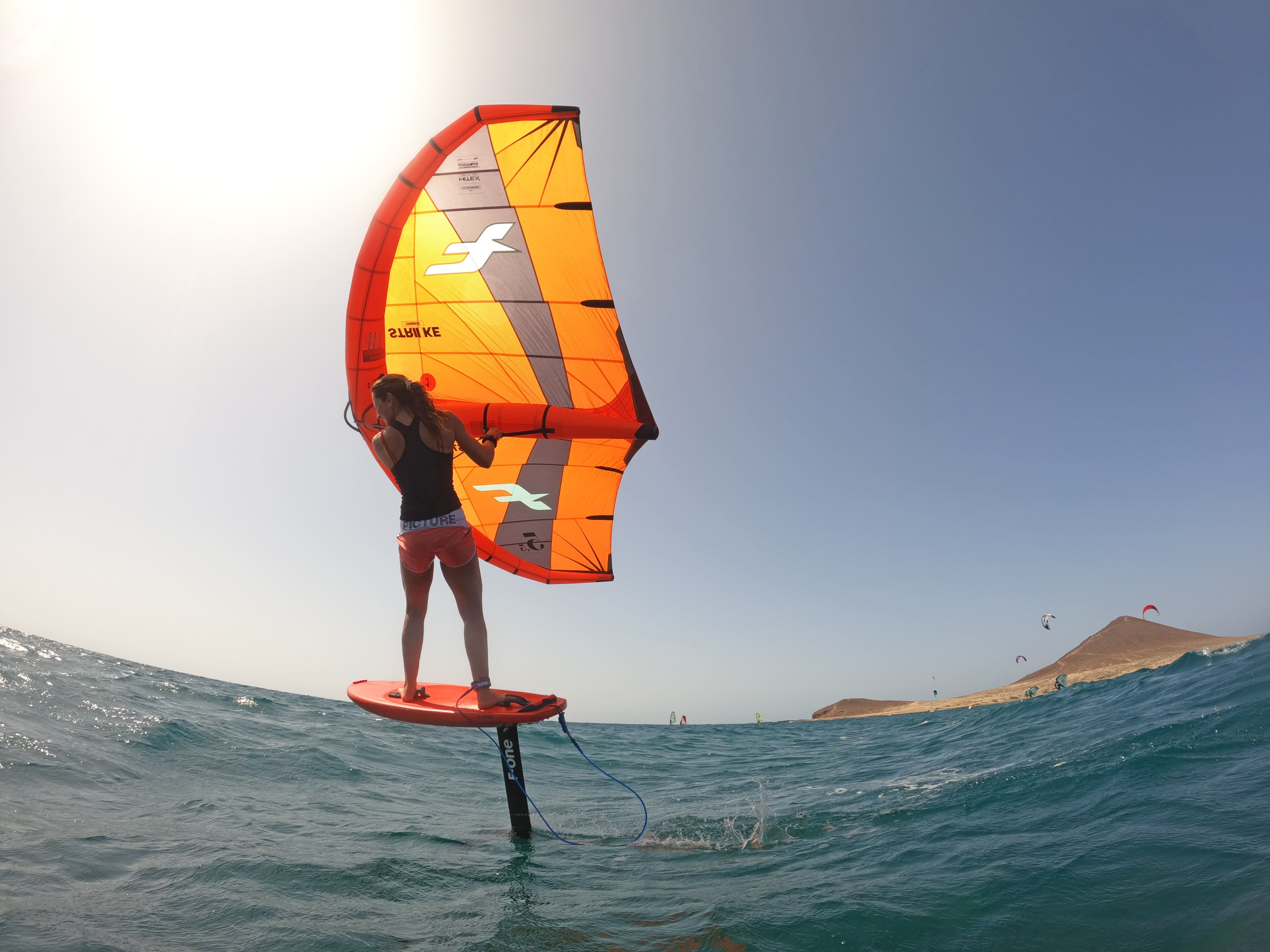 Persoon die wing foiling oefent in zee nabij het strand van El Médano, Tenerife.