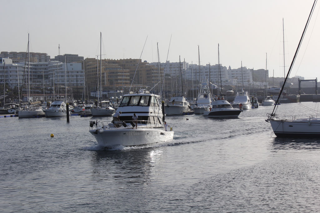 Boten in de haven van Los Cristianos, Tenerife, met gebouwen op de achtergrond.