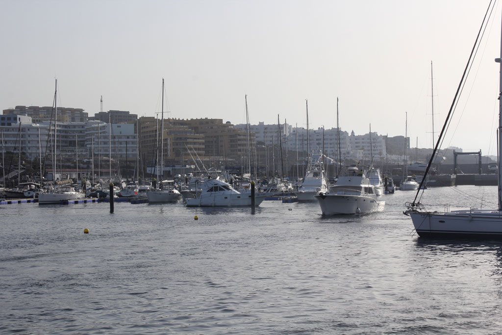 Boten in de haven van Los Cristianos, Tenerife, met gebouwen op de achtergrond.