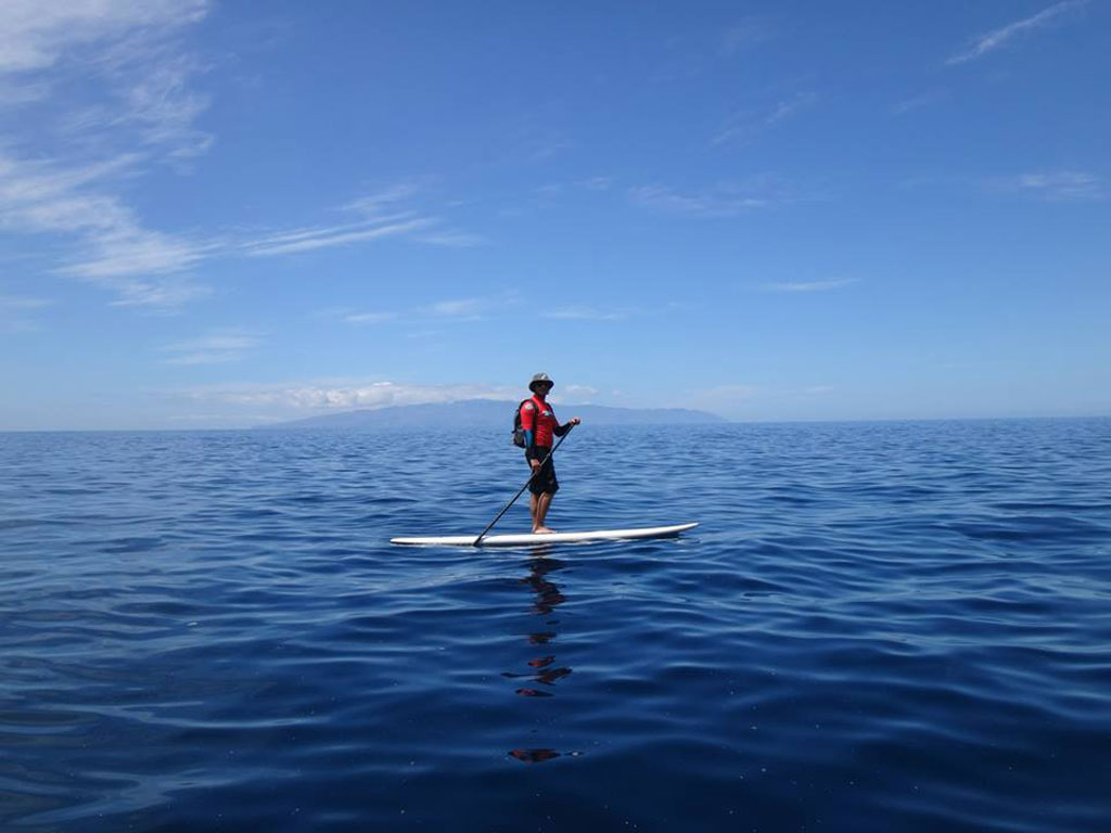 Persoon die paddlesurfen in zee nabij Tenerife beoefent.