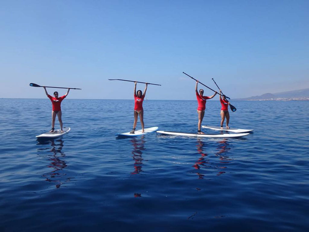 Vier mensen peddelen surfen in de zee van Tenerife.