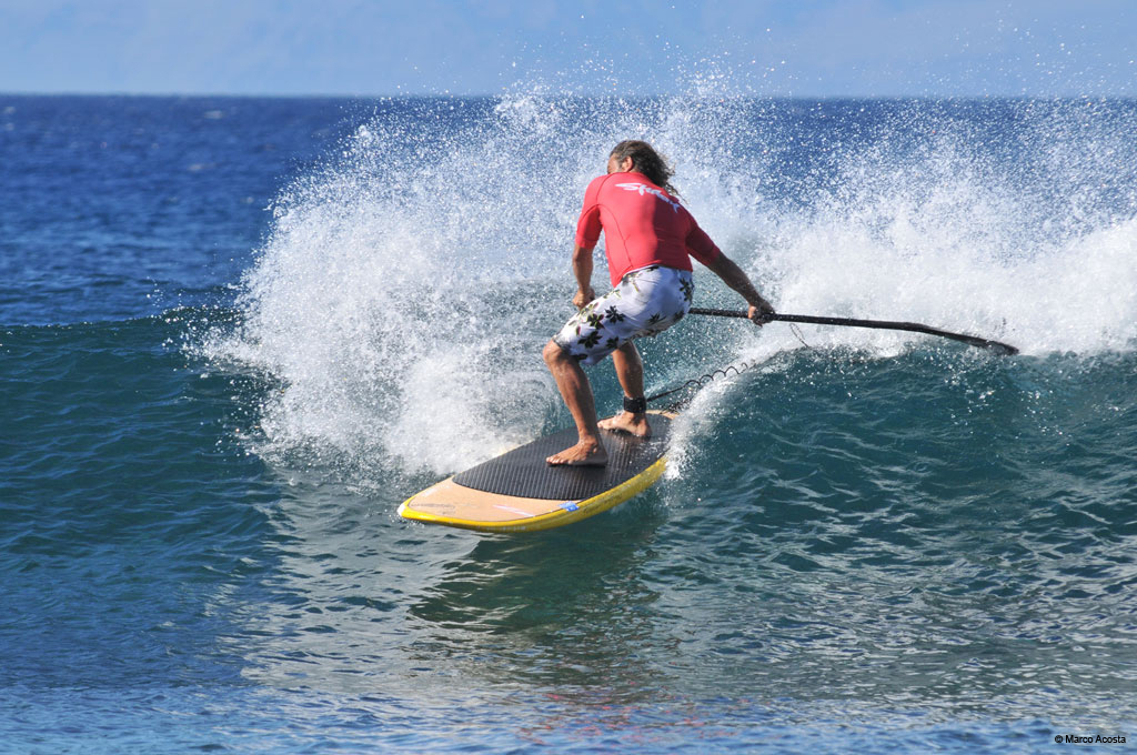 Persoon die stand-up paddleboardt in golven nabij de kust van Tenerife.