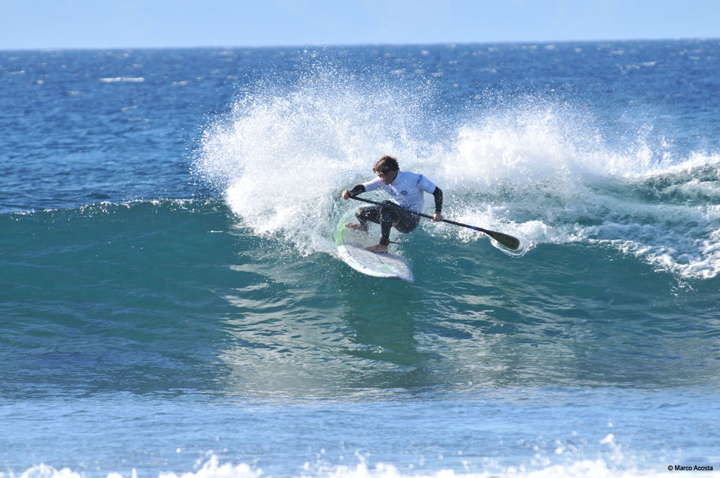 Persoon die stand-up paddleboardt op een golf voor de kust van Tenerife.