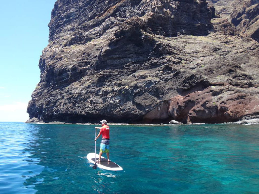 Persoon die paddleboardt bij een klif in Los Gigantes, Tenerife.