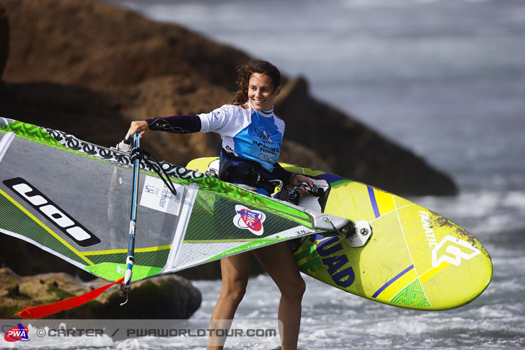 Persoon met windsurfuitrusting op het strand van Tenerife.