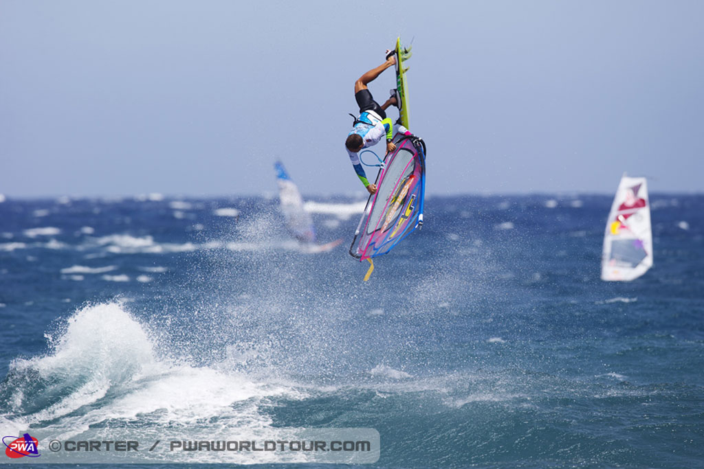 Persoon windsurft in El Médano, Tenerife, met zee- en andere zeilen op de achtergrond.