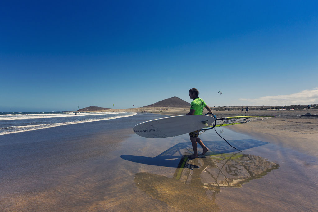 Persoon met windsurfplank op het strand van El Médano, Tenerife.
