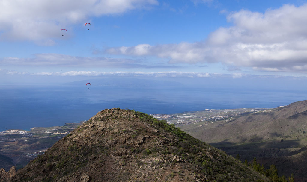 Paragliders vliegen over een berg op Tenerife met uitzicht op de oceaan.