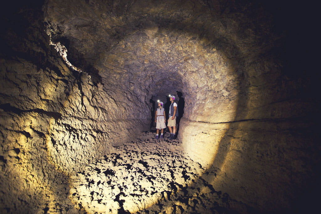 Ontdekkingsreizigers met zaklampen in een vulkanische tunnel op Tenerife.