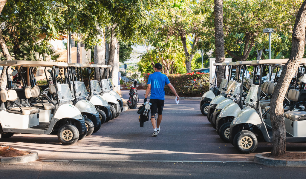 Man loopt tussen geparkeerde golfkarretjes op Tenerife.