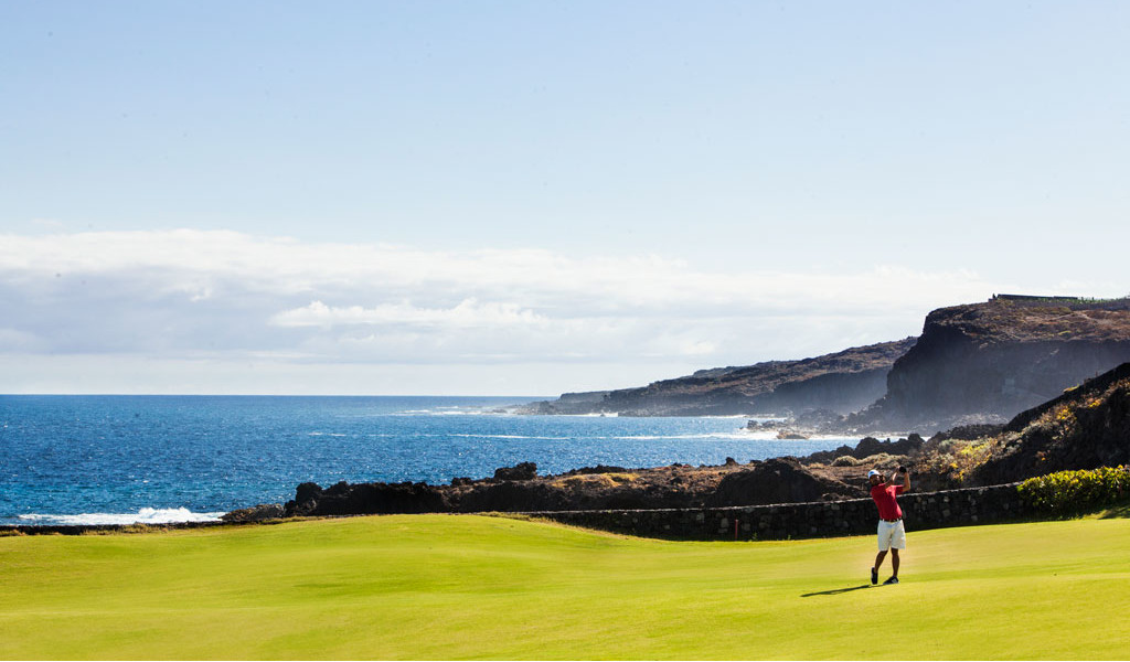 Iemand die golf speelt vlak bij de kust op Tenerife met de zee op de achtergrond.