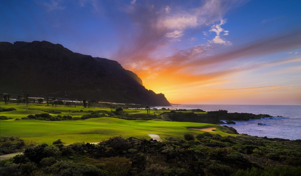 Zonsondergang boven een golfbaan op Tenerife aan zee.