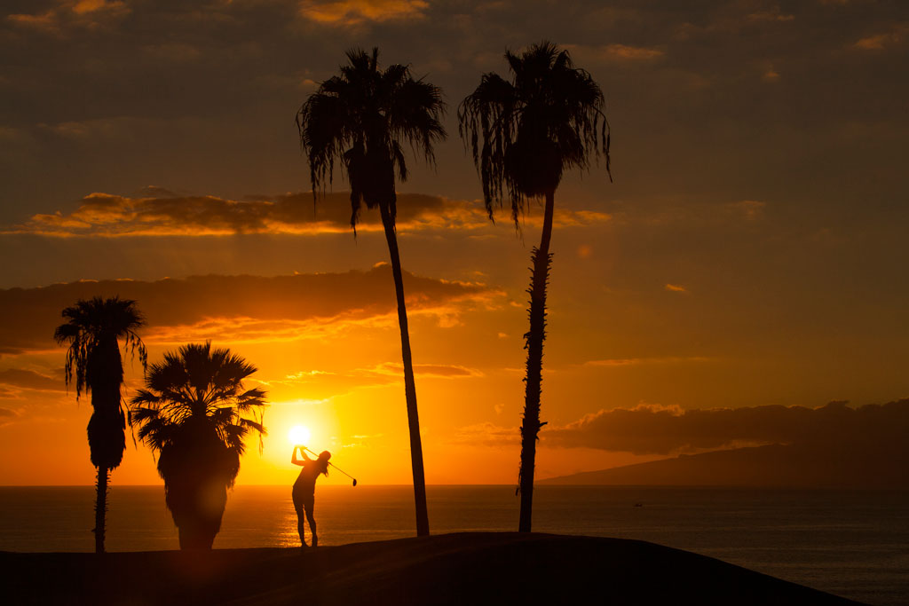 Zonsondergang met palmbomen en iemand die golf speelt op Tenerife.