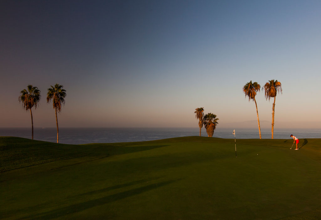 Golfbaan bij zonsondergang met palmbomen en een speler op Tenerife.