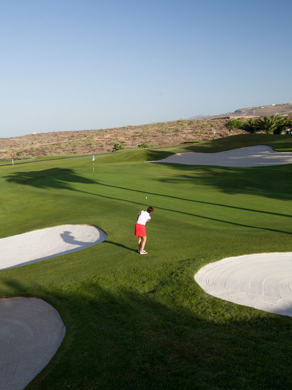 Golfer op de Abama-baan op Tenerife, vlakbij de hole en een bunker.