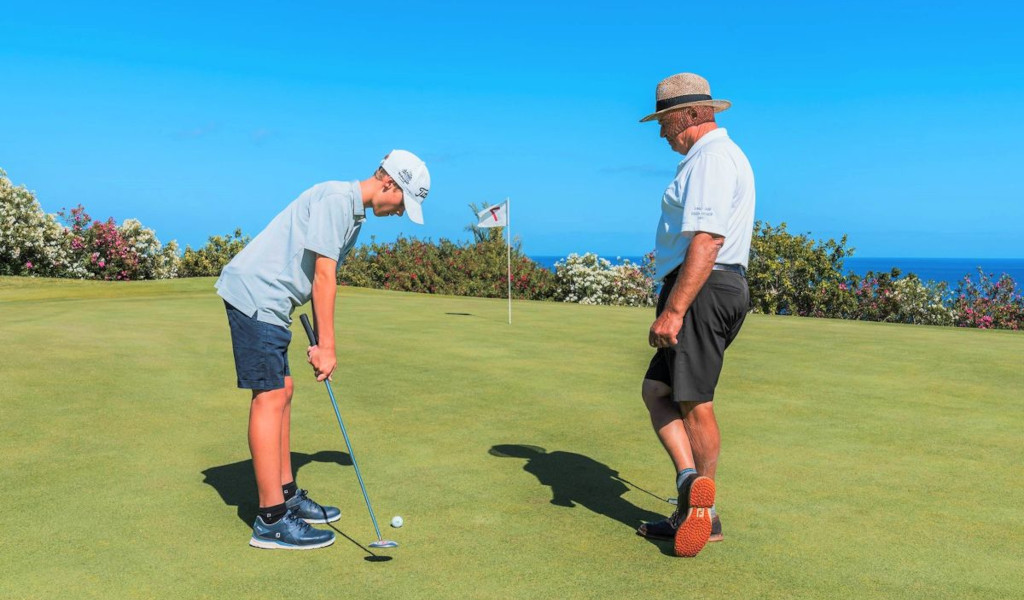 Kind dat golf speelt met een volwassene op de achtergrond, Tenerife.
