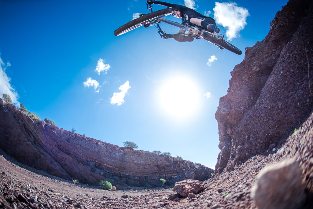 Fietser in extreme sprong in een canyon op Tenerife onder heldere lucht.