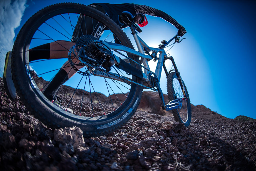 Mountainbiker over rotsachtig terrein op Tenerife onder een blauwe lucht.