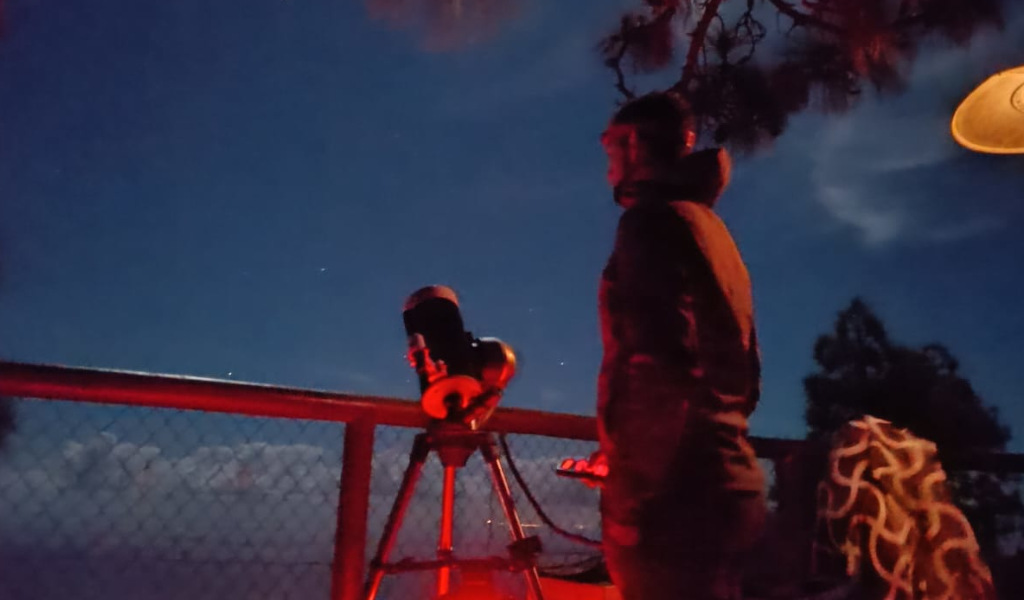Persoon die de nachtelijke hemel observeert met een telescoop, mogelijk op Tenerife.