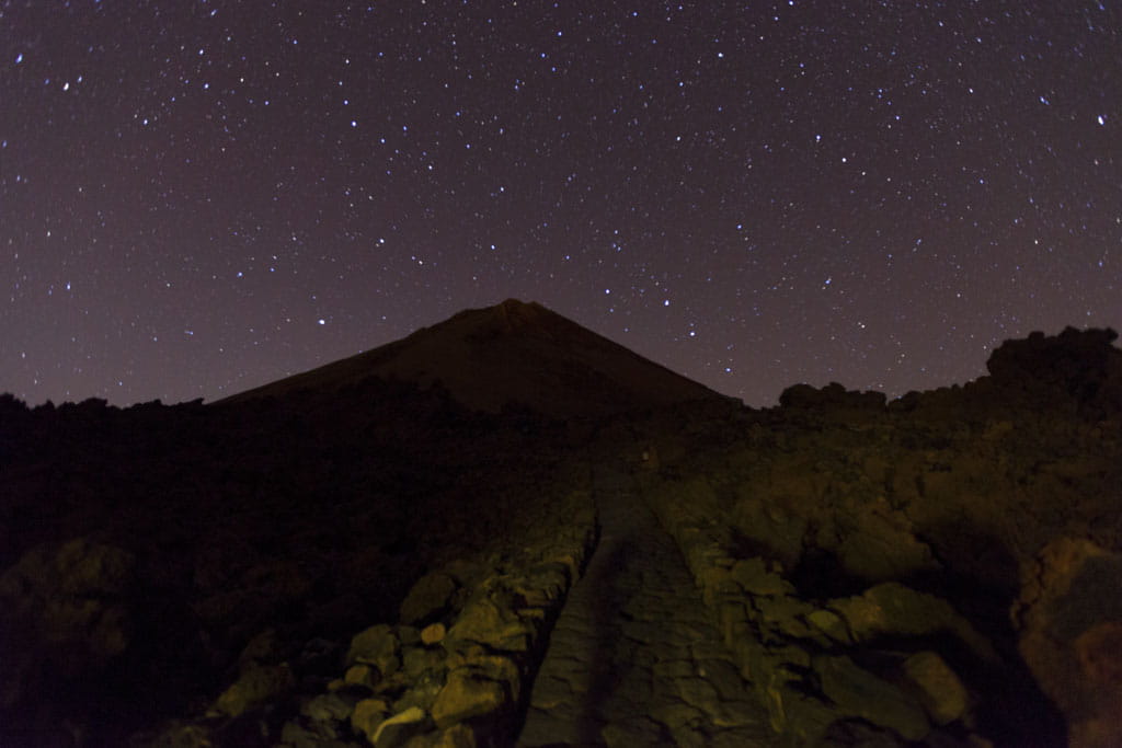 Sterrenhemel boven de berg Teide op Tenerife, met een rotsachtig pad op de voorgrond.