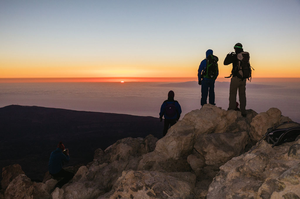 Bergbeklimmers die de zonsopgang bekijken vanaf de top van de berg Teide op Tenerife.