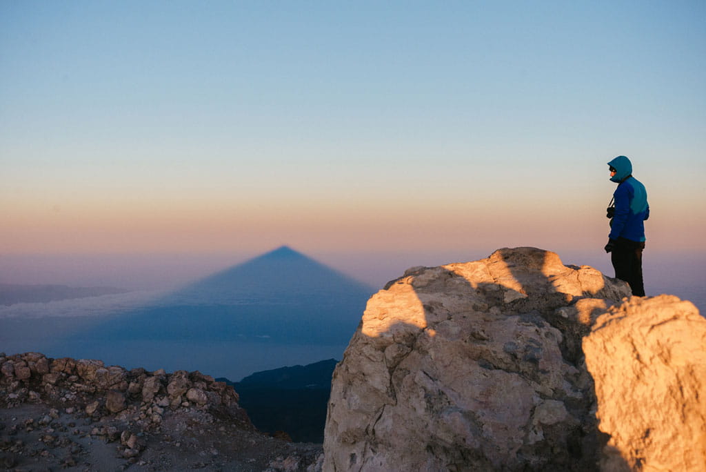Persoon die de schaduw van de Pico del Teide bij zonsopgang op Tenerife observeert.