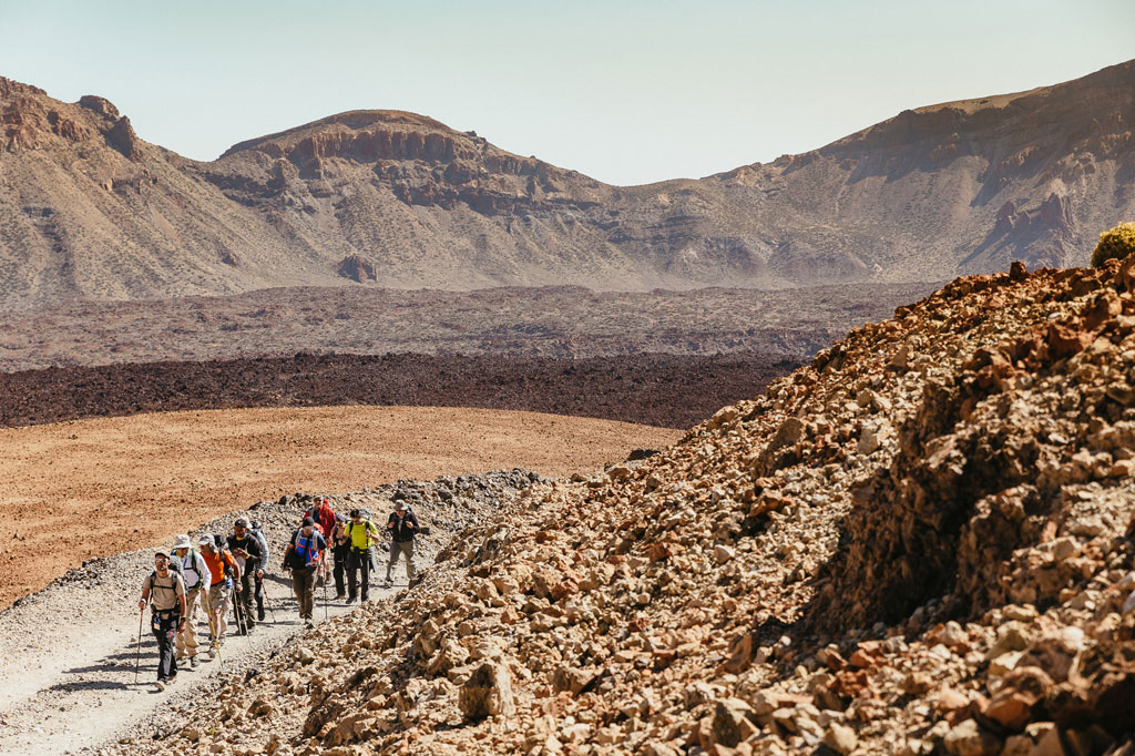 Groep wandelaars op een rotsachtig pad in Nationaal Park Teide, Tenerife.