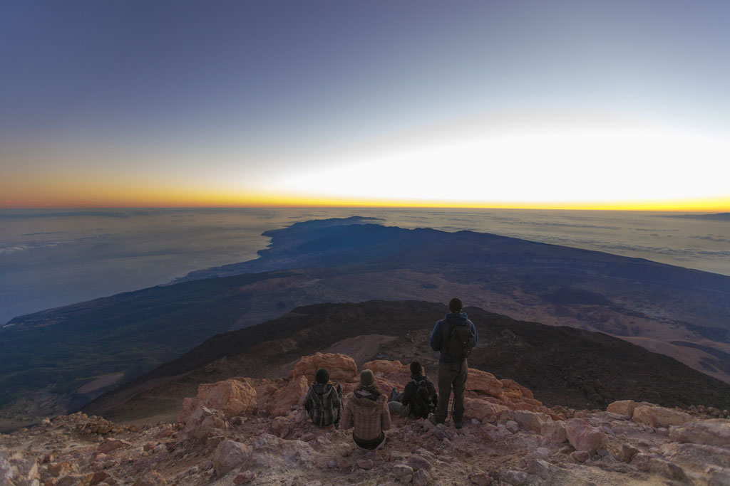 Zonsopgang op de berg Teide, Tenerife, met mensen die vanaf de top naar het landschap kijken.