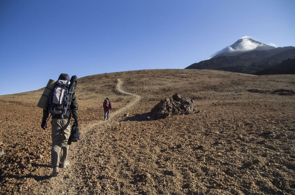 Wandel naar de berg Teide op Tenerife met twee wandelaars die lopen.