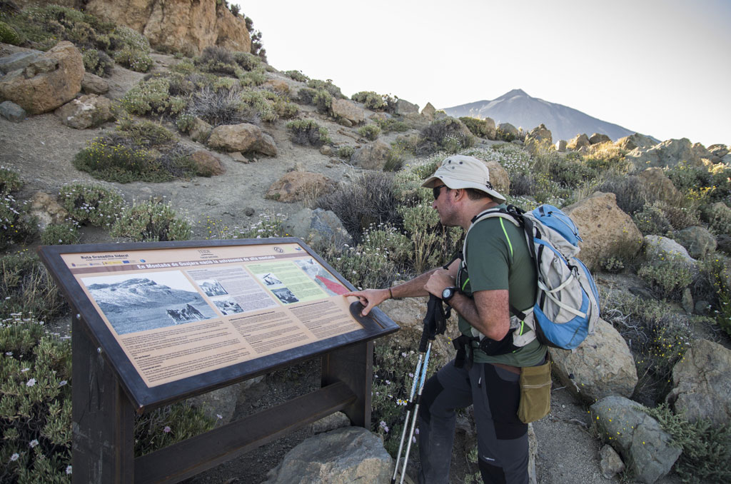 Wandelaar leest een informatiebord over het Nationaal Park Teide op Tenerife.